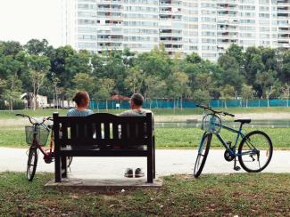man and woman sitting on bench near two bikes viewing green field during daytime by Nguyen Thu Hoai courtesy of Unsplash.