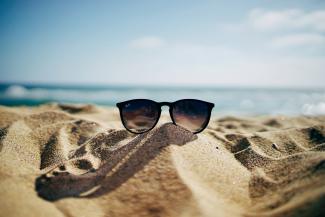 black Ray-Ban Wayfarer sunglasses on beach sand by Ethan Robertson courtesy of Unsplash.